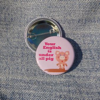 Ansteckbutton Your English is under all pig auf Jeans mit Rückseite